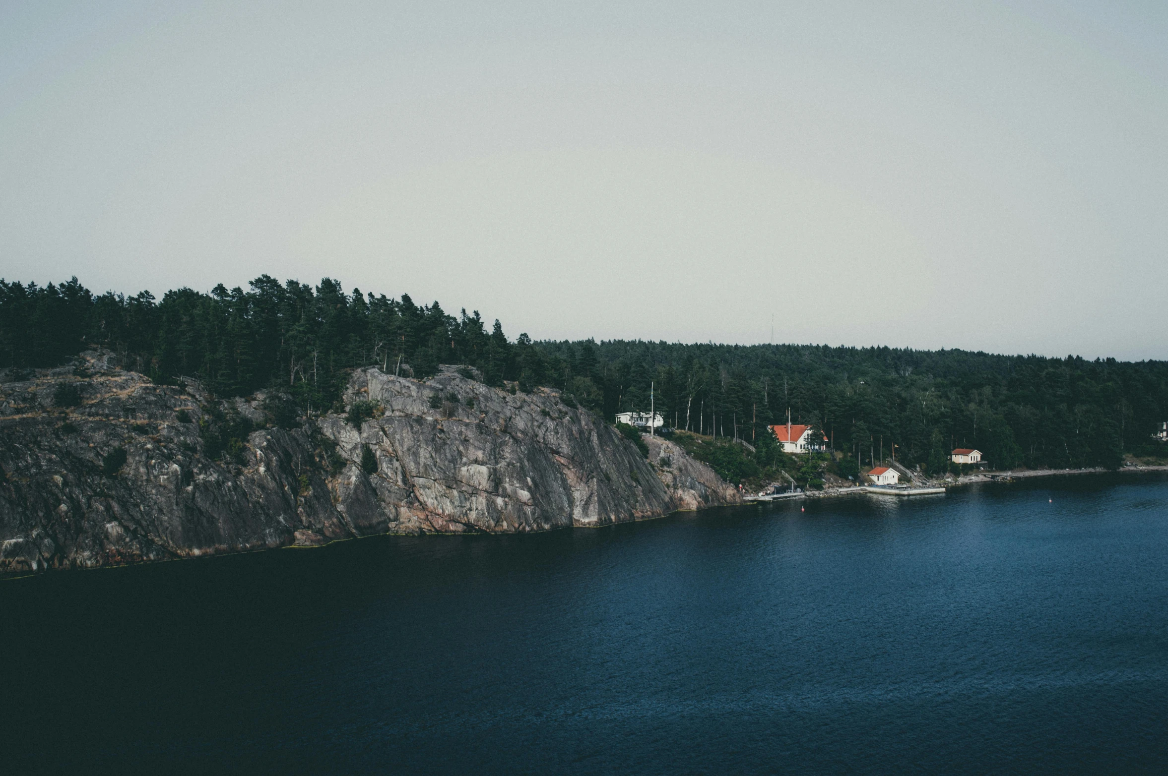 a large body of water next to a forest, by Jesper Knudsen, pexels contest winner, minimalism, cliffside town, archipelago, low quality photo, 2 0 0 0's photo