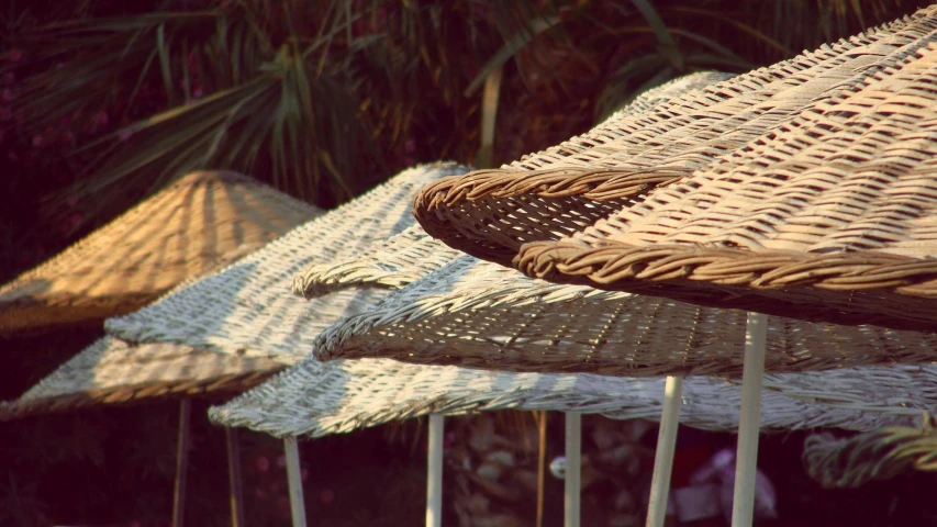 a group of straw umbrellas sitting next to each other, an album cover, unsplash, cairo, late afternoon, vintage photo, tables and chairs