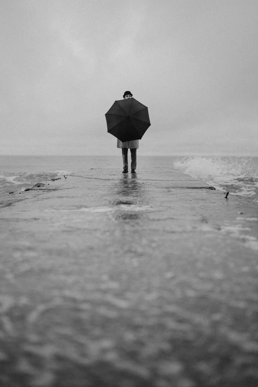 a person standing in the water with an umbrella, a black and white photo, by Felix-Kelly, the sea of sadness, made out of rain, hziulquoigmnzhah, zac retz