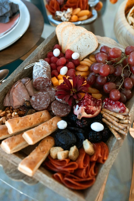 a table topped with lots of different types of food, on a wooden plate, fruit, up-close, bread