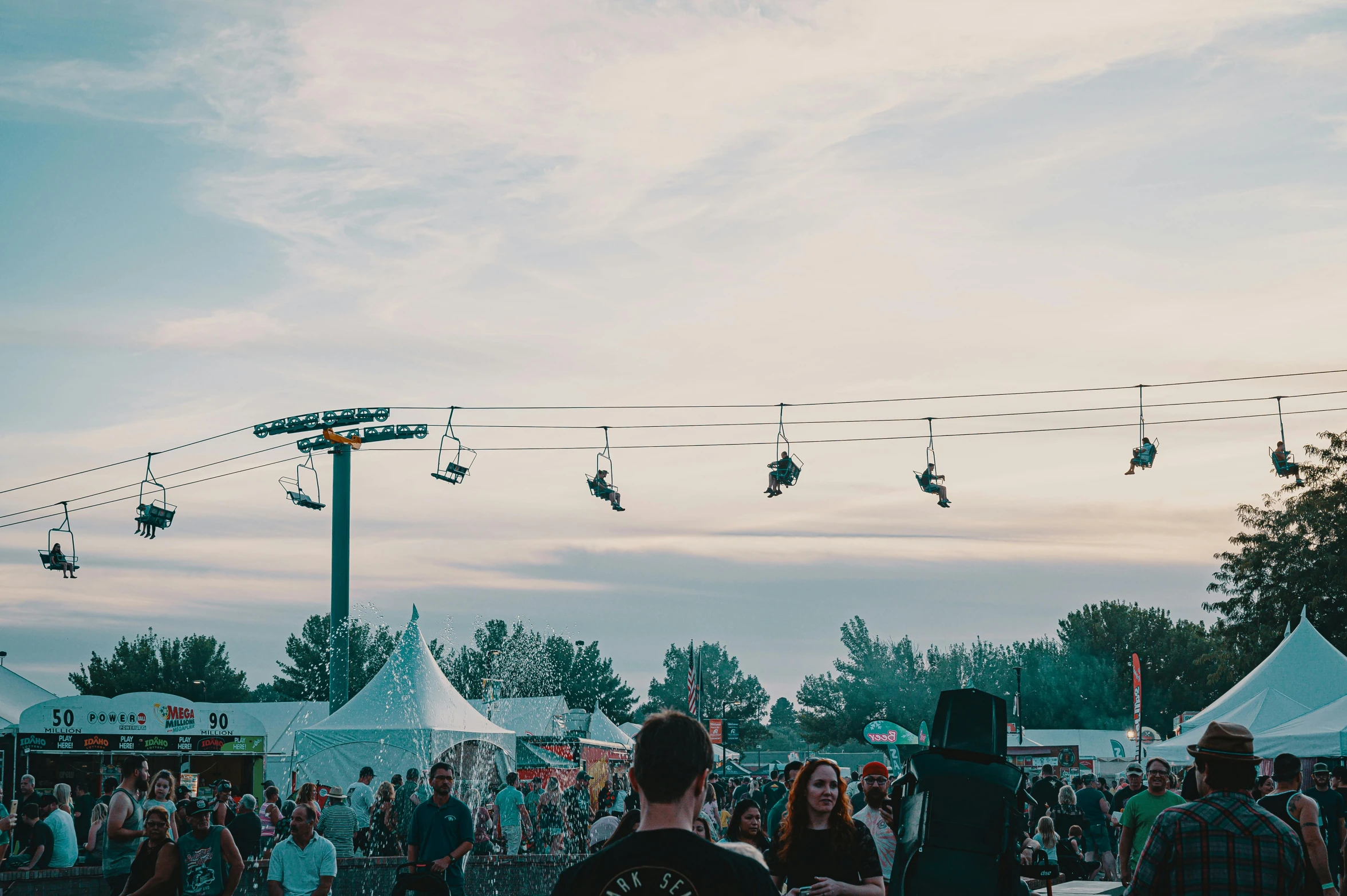 a group of people that are standing in the grass, festival vibes, chairlifts, well lit sky, things hanging from ceiling