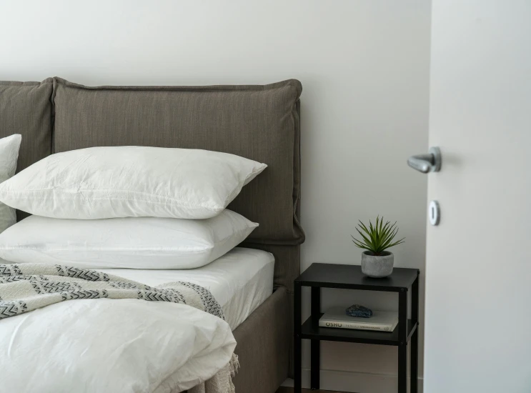 a couple of pillows sitting on top of a bed, by Adam Marczyński, pexels contest winner, white mechanical details, small bedroom, grey, 3 - piece