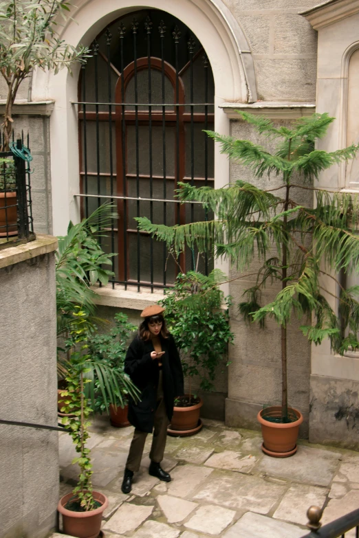 a man standing in a courtyard with potted plants, pexels contest winner, renaissance, spruce trees, old apartment, ignant, imaan hammam