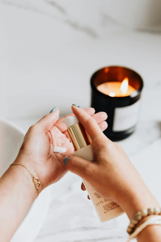 a woman using a hand sanitizer to clean her hands, by Julia Pishtar, trending on pexels, holding a candle, marble and hint gold, handcrafted, profile image