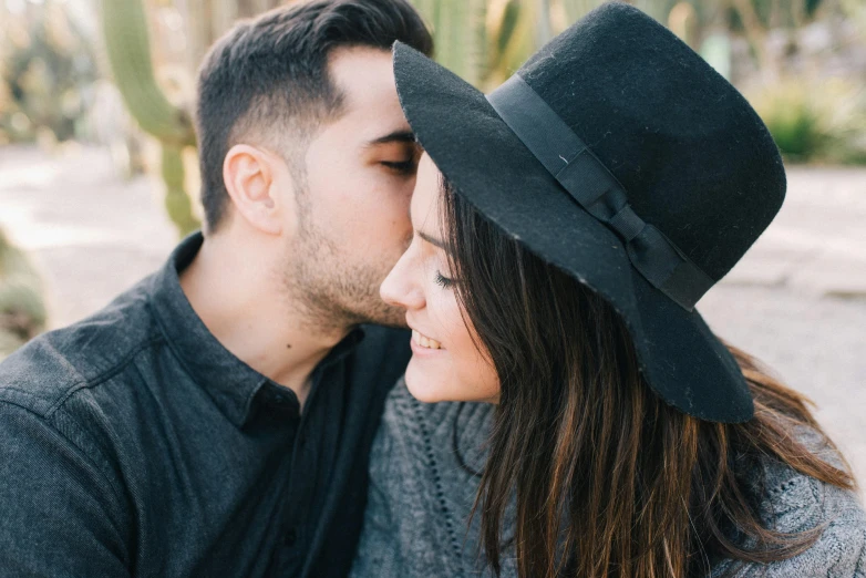 a man and a woman sitting next to each other, pexels contest winner, romanticism, wearing a cute hat, profile image, kiss mouth to mouth, black pointed hat
