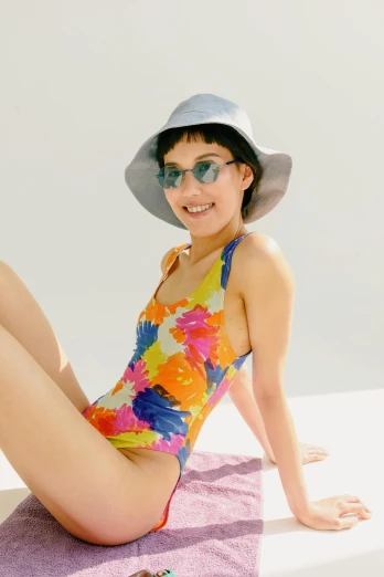 a woman sitting on top of a purple towel, wearing sunglasses and a hat, skintight rainbow body suit, kiko mizuhara, floral