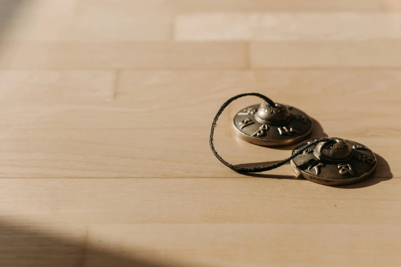 a pair of headphones sitting on top of a wooden table, by Jesper Knudsen, trending on pexels, close up shot of an amulet, sundial, beige, background image