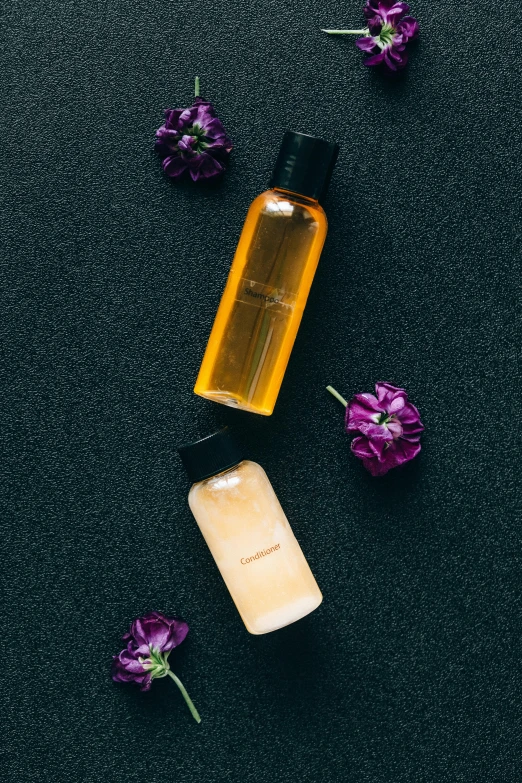 a bottle of essential oil next to purple flowers, by Julia Pishtar, unsplash, hair gel combed backwards, on a black background, bottles covered in wax, japanese collection product