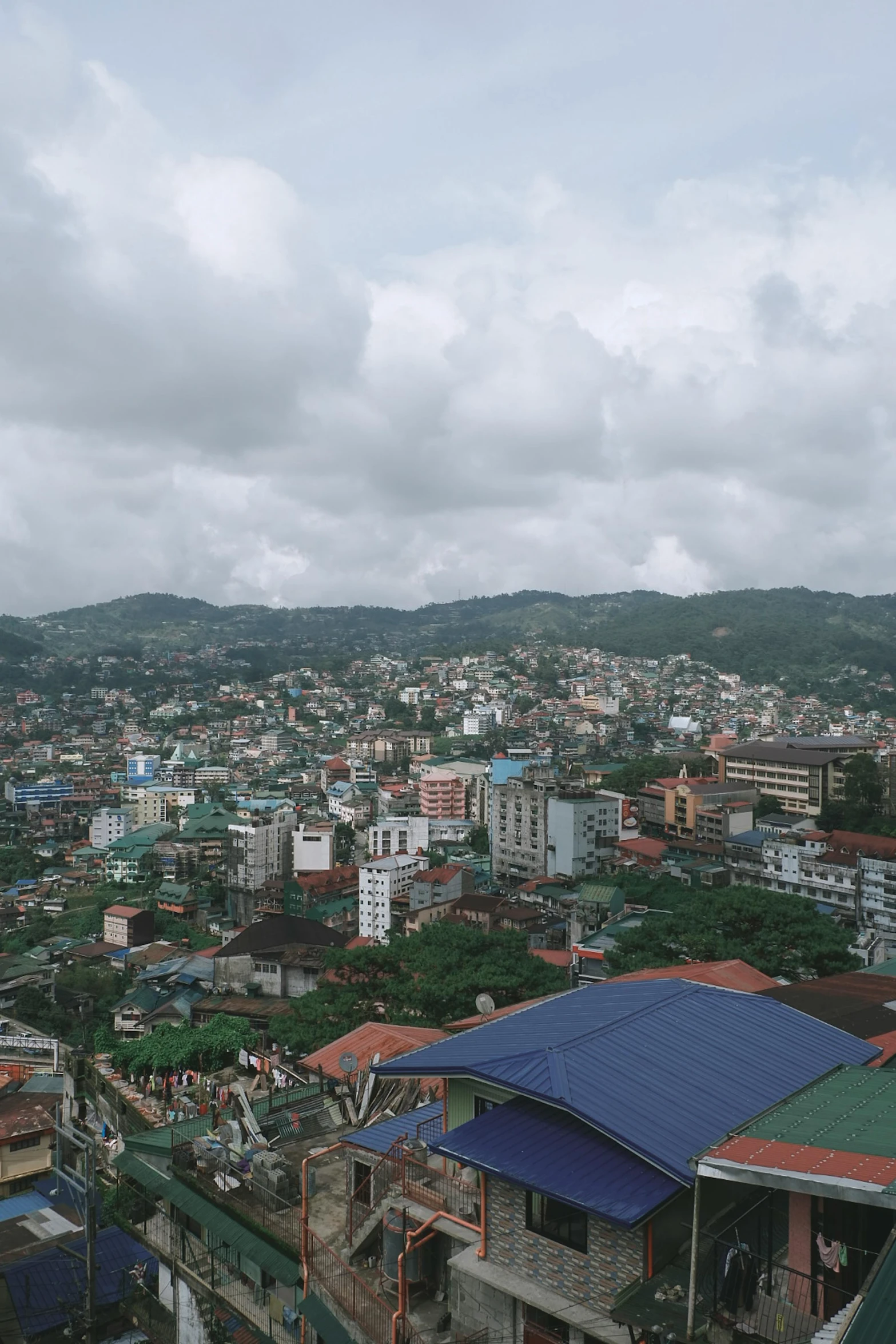 a view of a city from the top of a building, sumatraism, view(full body + zoomed out), hills, old town, looking sad