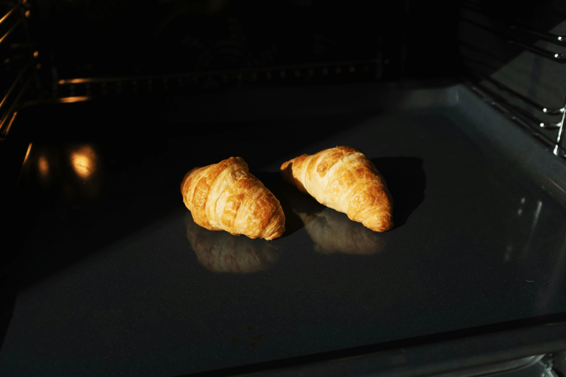 two croissants sitting on top of an oven, inspired by Károly Patkó, unsplash, fluorescent, sun glints, ignant, shot on sony a 7