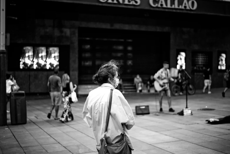 a black and white photo of a man standing in front of a movie theater, by Tamas Galambos, in barcelona, musician, her back is to us, deiv calviz