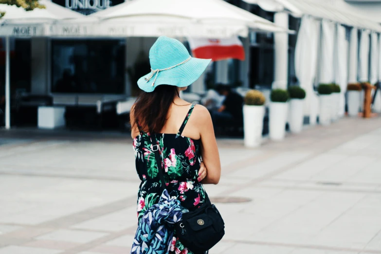 a woman in a floral dress and a blue hat, unsplash, at a mall, turquoise, from back, hot day