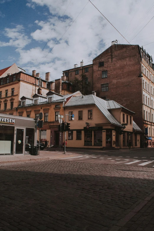a man riding a skateboard down a street next to tall buildings, by Adam Marczyński, pexels contest winner, art nouveau, swedish house, fresh bakeries in the background, cobblestone, panorama