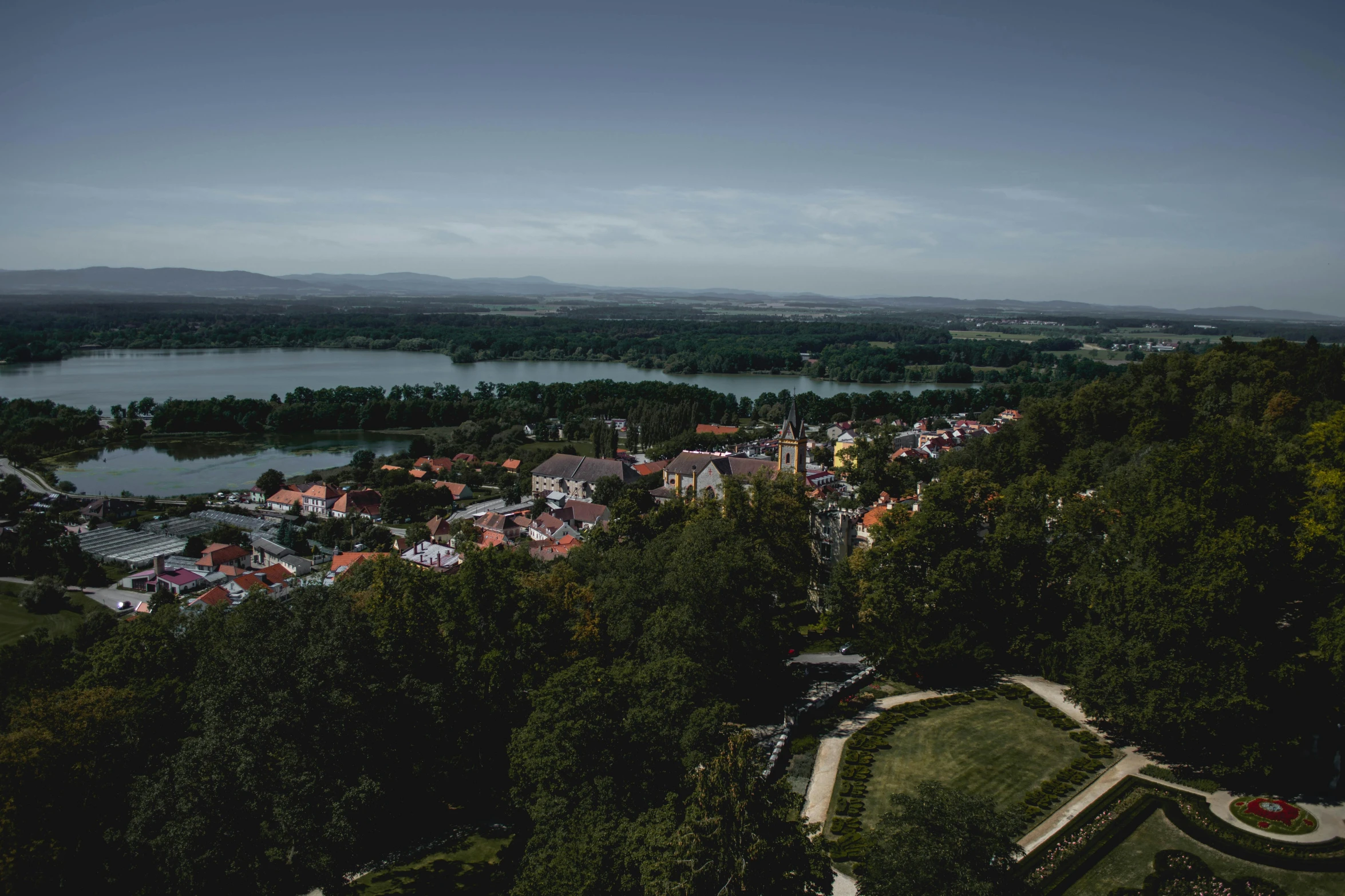 a view of a town from the top of a hill, by Sebastian Spreng, pexels contest winner, happening, parks and lakes, ultrawide angle cinematic view, small castle in the distance, trees in the background