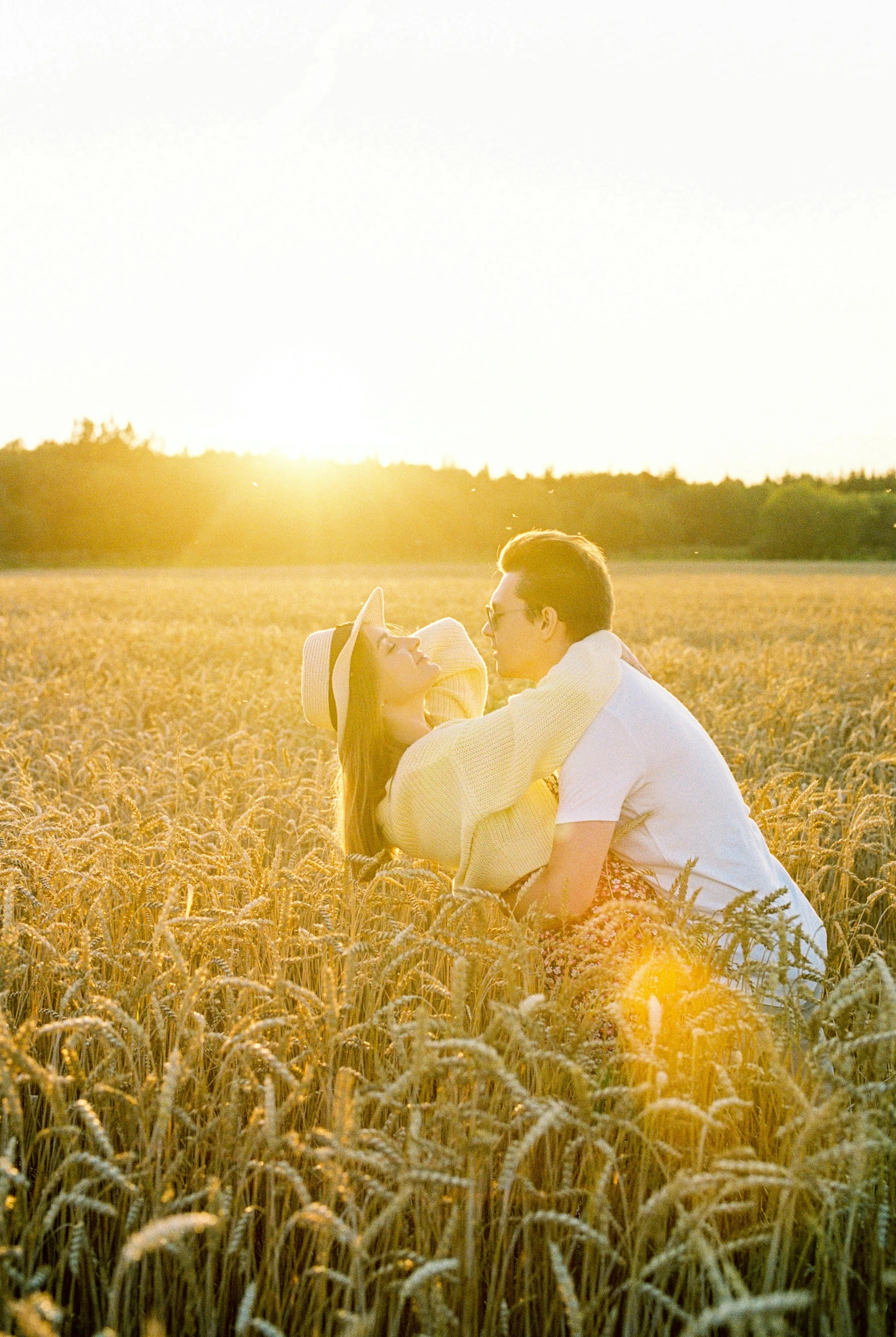 a man and woman kissing in a field of wheat, with the sun shining on it, rectangle, photograph, white