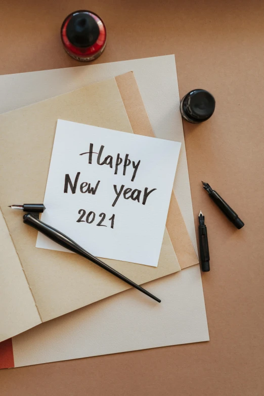 a note with the words happy new year written on it, trending on pexels, happening, black fine lines on warm brown, 2 0 2 1, calligraphy formula, thumbnail