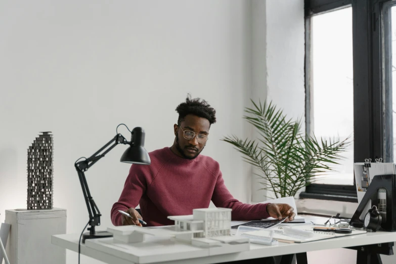 a man sitting at a desk working on a laptop, inspired by Afewerk Tekle, pexels contest winner, arbeitsrat für kunst, architect studio, portrait of tall, 1 2 9 7, rj palmer