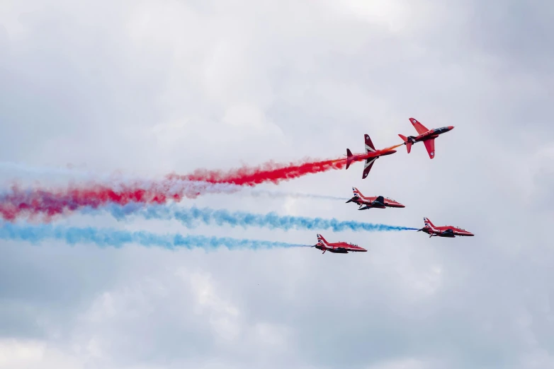 a group of jets flying through a cloudy sky, by Paul Bird, pexels contest winner, wearing red attire, brand colours are red and blue, 1024x1024, curved red arrow