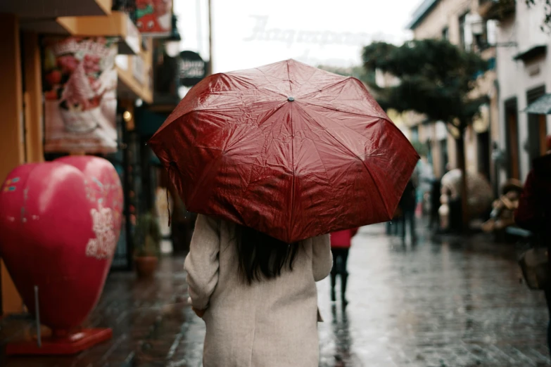 a woman walking down a street holding a red umbrella, pexels contest winner, rain and thick strands of mucus, maroon, instagram post, videogame still