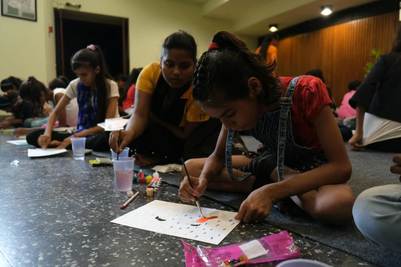 a group of children sitting on the floor drawing, bengal school of art, painting on a badge, animation still, drawn with dots, in a workshop