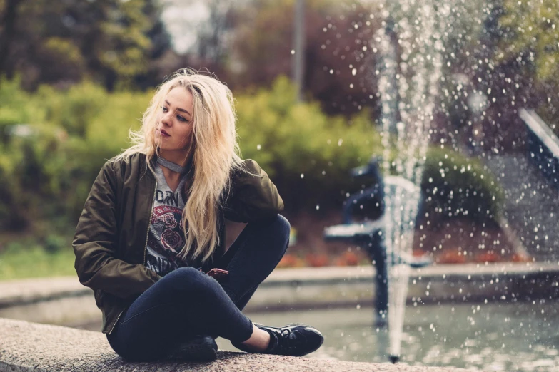 a woman sitting on a ledge next to a fountain, trending on unsplash, messy blonde hair, an emo girl, woman in streetwear, joel fletcher