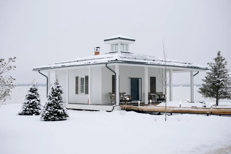 a white house sitting on top of a snow covered field, inspired by Eero Snellman, unsplash, hurufiyya, with a front porch, white sky, exterior view, architectural digest