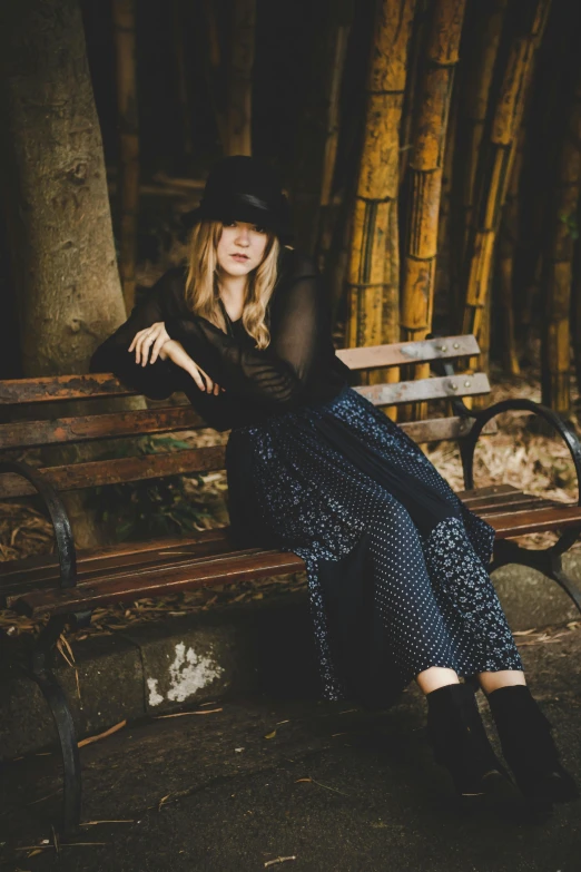 a woman sitting on top of a wooden bench, inspired by Anna Boch, pexels contest winner, renaissance, wearing modern gothic clothes, sydney sweeney, pants, baggy clothing and hat