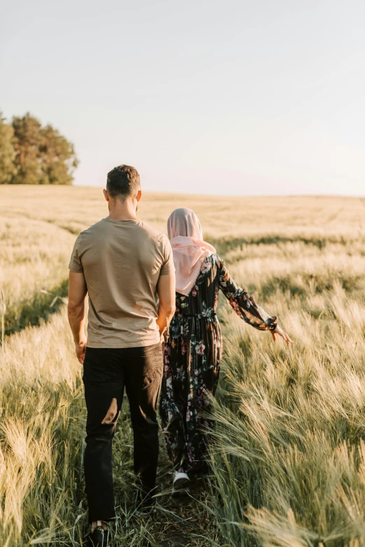 a man and a woman walking through a wheat field, pexels contest winner, hurufiyya, hijab, swedish countryside, with his back turned, looking seductive