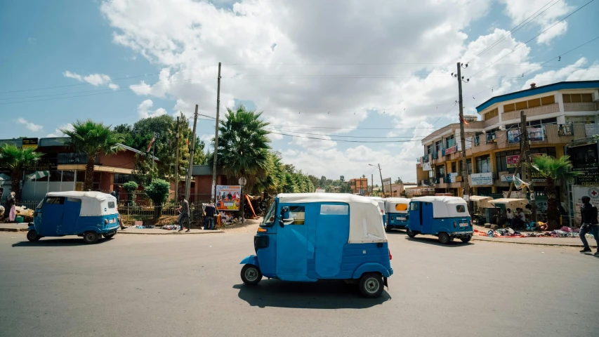 a blue and white tuk - tuk driving down a street, an album cover, trending on unsplash, hurufiyya, ethiopian, in a suburb, slide show, unmistakably kenyan