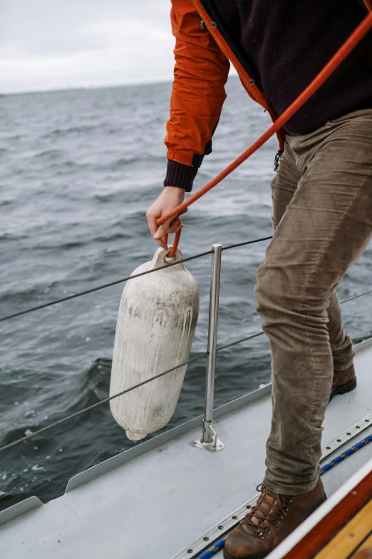 a man that is standing on a boat, sharing an oxygen tank, head down, grey, sustainability