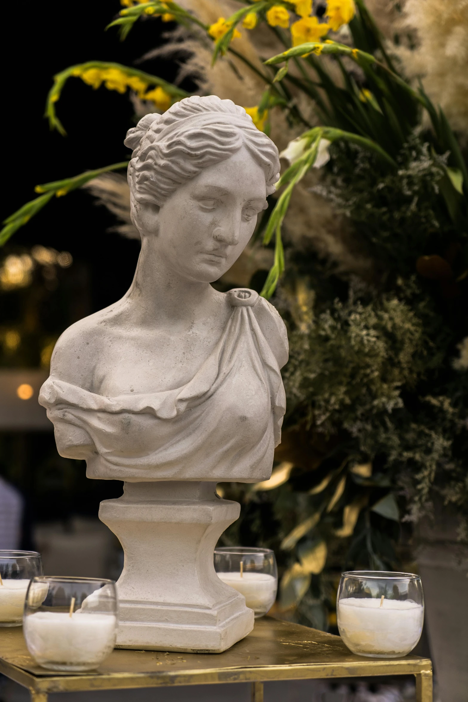 a statue sitting on top of a table next to candles, a marble sculpture, garden setting, up close, elegant face, fine dining