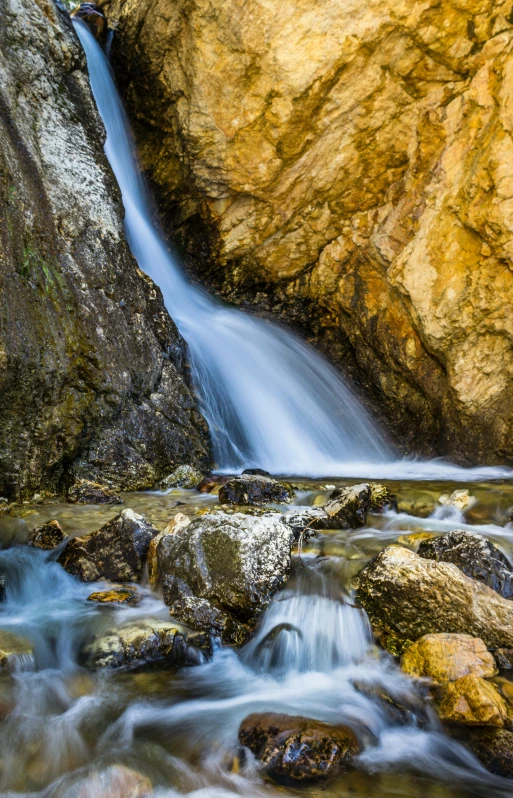 a waterfall flowing over rocks into a river, a picture, by Karl Walser, shutterstock contest winner, malibu canyon, today\'s featured photograph 4k, liquid gold, slide show