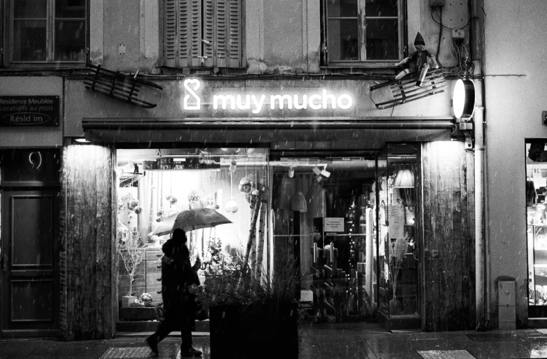 a black and white photo of a person holding an umbrella, a black and white photo, by Muqi, art nouveau, des boutiques avec des neons, night outside, miro, yummy