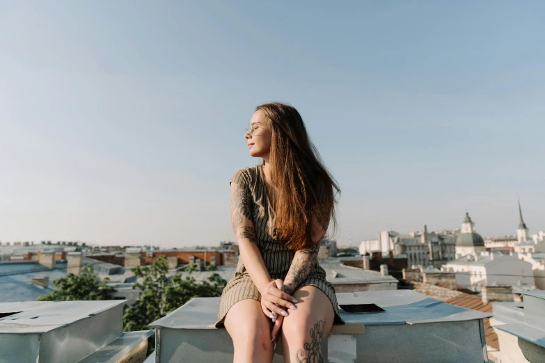 a woman sitting on the roof of a building, a portrait, trending on pexels, with tattoos, smiling girl, freckled pale skin, profile pic