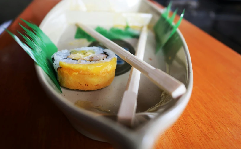 a plate of sushi and chopsticks on a table, unsplash, mingei, sitting in a small bamboo boat, yellow, 2 0 0 0's photo, low angle photo