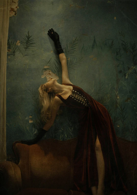 a woman in a red dress laying on a couch, an album cover, inspired by Brooke Shaden, hands up, lady dimitrescu, ava max, in a dark dusty parlor