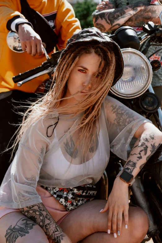 a woman sitting on the back of a motorcycle, a tattoo, inspired by Elsa Bleda, trending on pexels, photorealism, dreadlock hair, sexy face, official music video, looking smart