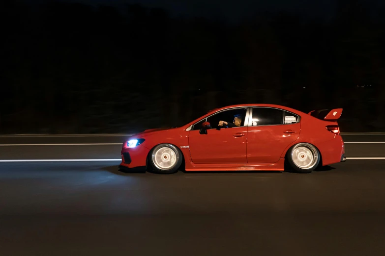 a red car driving down a road at night, wrx golf, soft rim light, profile picture, vollumetric lighting