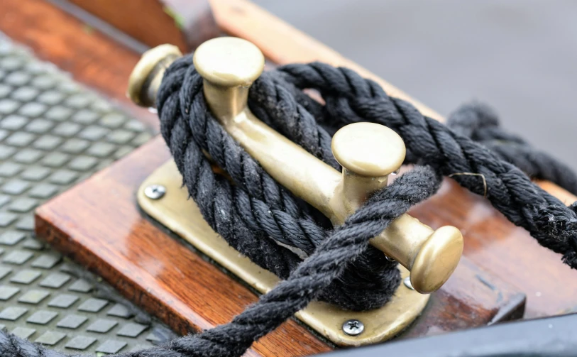 a close up of a rope on a boat, an album cover, inspired by Horatio Nelson Poole, trending on pexels, arts and crafts movement, brass wheels, ebony wood bow, thumbnail, small boat