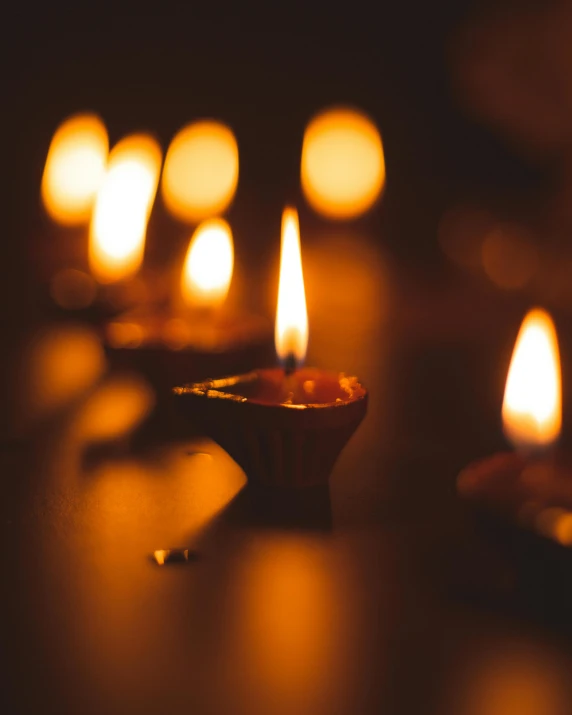 a group of lit candles sitting on top of a table, profile image, hindu aesthetic, lgbtq, lamplight