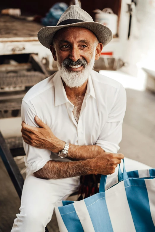 a man that is sitting down with a bag, pexels contest winner, photorealism, short white beard, caracter with brown hat, middle eastern skin, wearing a white button up shirt