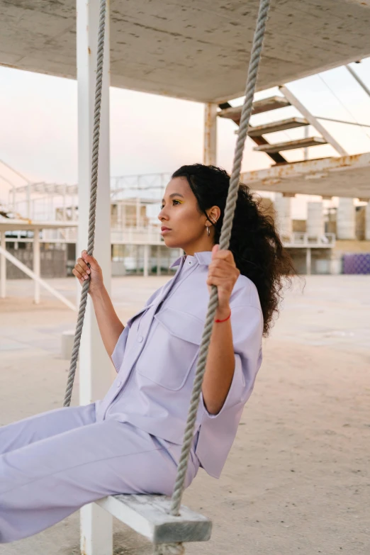 a woman that is sitting on a swing, trending on pexels, arabesque, wearing a linen shirt, wearing a track suit, featuring wires, freida pinto