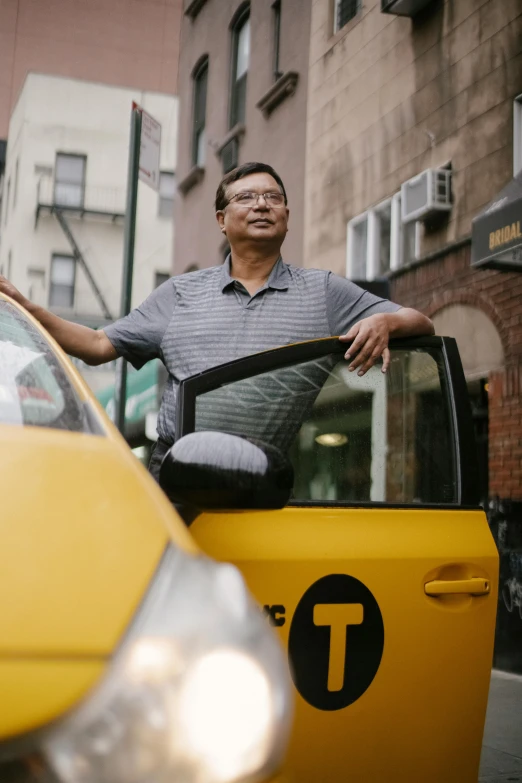 a man standing next to a yellow taxi cab, renaissance, asian descent, ignant, new york times, man with glasses