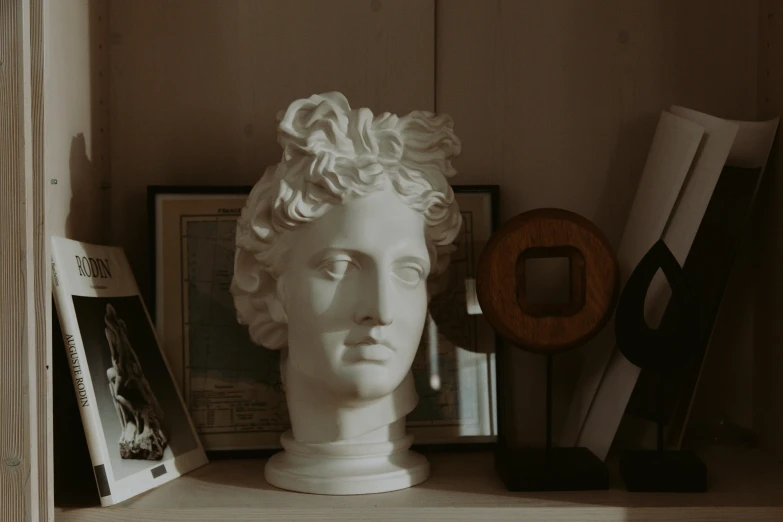 a close up of a bust of a person on a shelf, inspired by Antonio Canova, trending on pexels, decoration around the room, classical animation, low quality photograph, male with halo