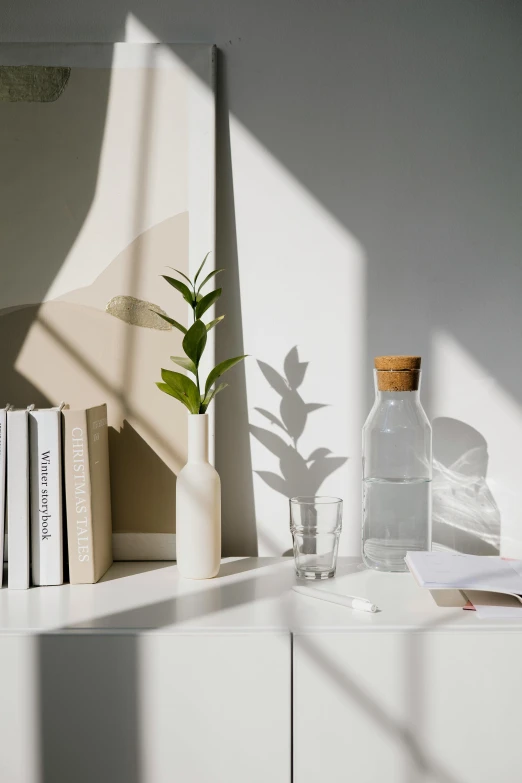 a vase sitting on top of a white shelf next to a mirror, unsplash contest winner, light and space, water light scattering, papers on table, glass bottle, full morning sun