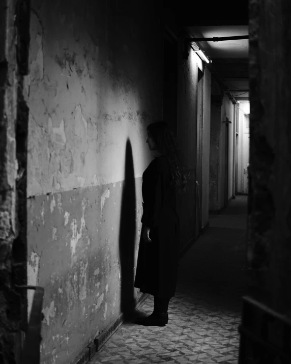 a black and white photo of a person standing in a hallway, pexels contest winner, dark coat, anna nikonova, an intruder, ilustration