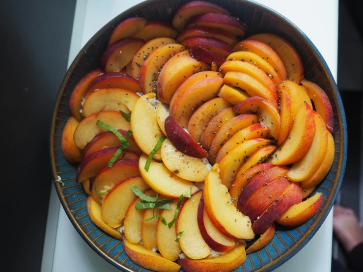 a bowl filled with sliced peaches on top of a table, multicoloured, over-the-shoulder shot, unedited, bowl filled with food