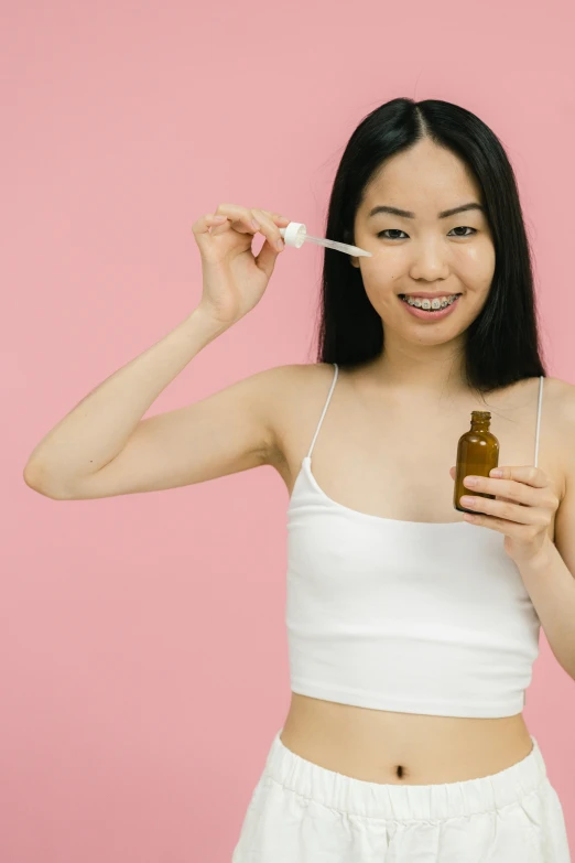 a woman holding a bottle and toothbrush in front of her face, trending on pexels, ethnicity : japanese, bubblegum body, made of liquid, manuka