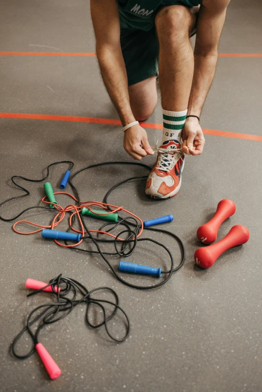 a man kneeling on the ground with a bunch of jump rope, by Matthias Stom, trending on pexels, indoor picture, ilustration, coloured, 15081959 21121991 01012000 4k