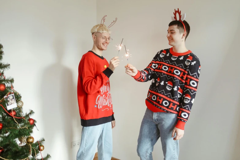 a couple of men standing next to a christmas tree, pexels contest winner, wearing a sweater, short antlers, avatar image, full body photo